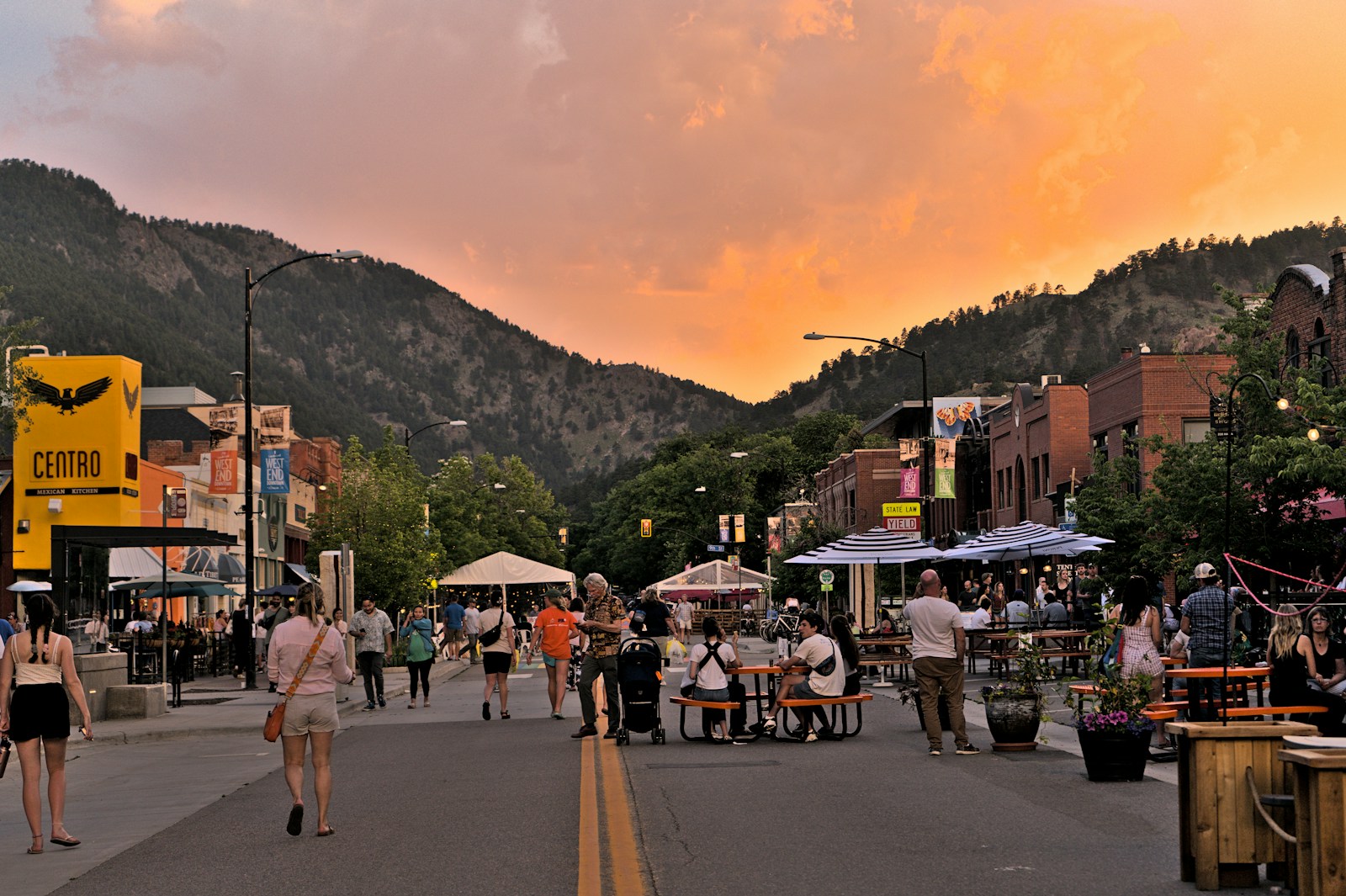 a group of people walking on a street with mountains in the background, longmont junk removal